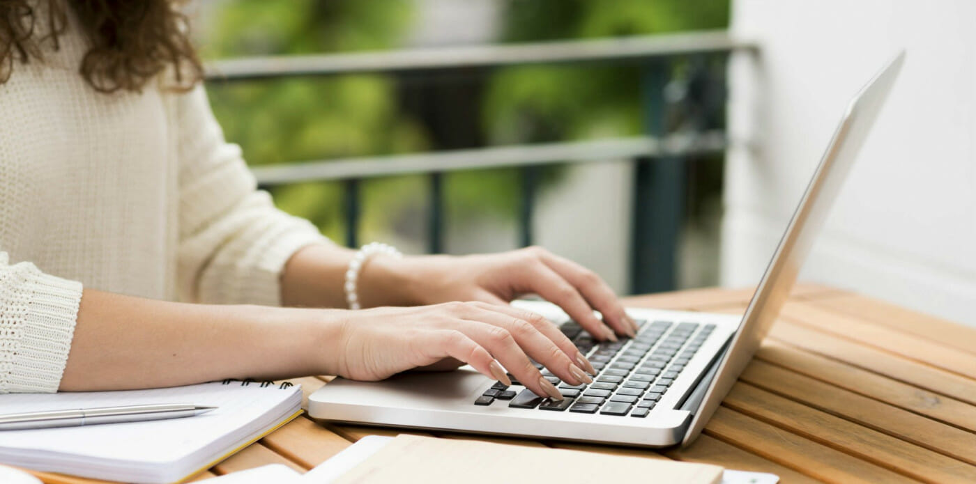 Una ragazza scrive al computer portatile seduta a una scrivania