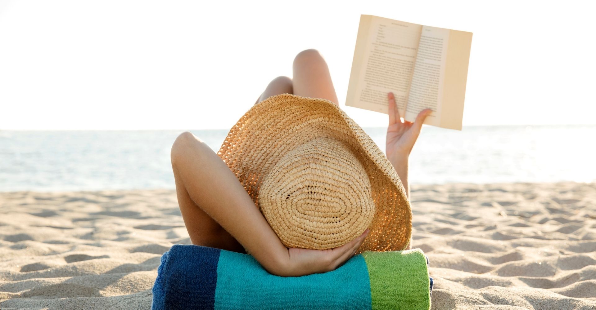 Una donna che legge un libro in spiaggia