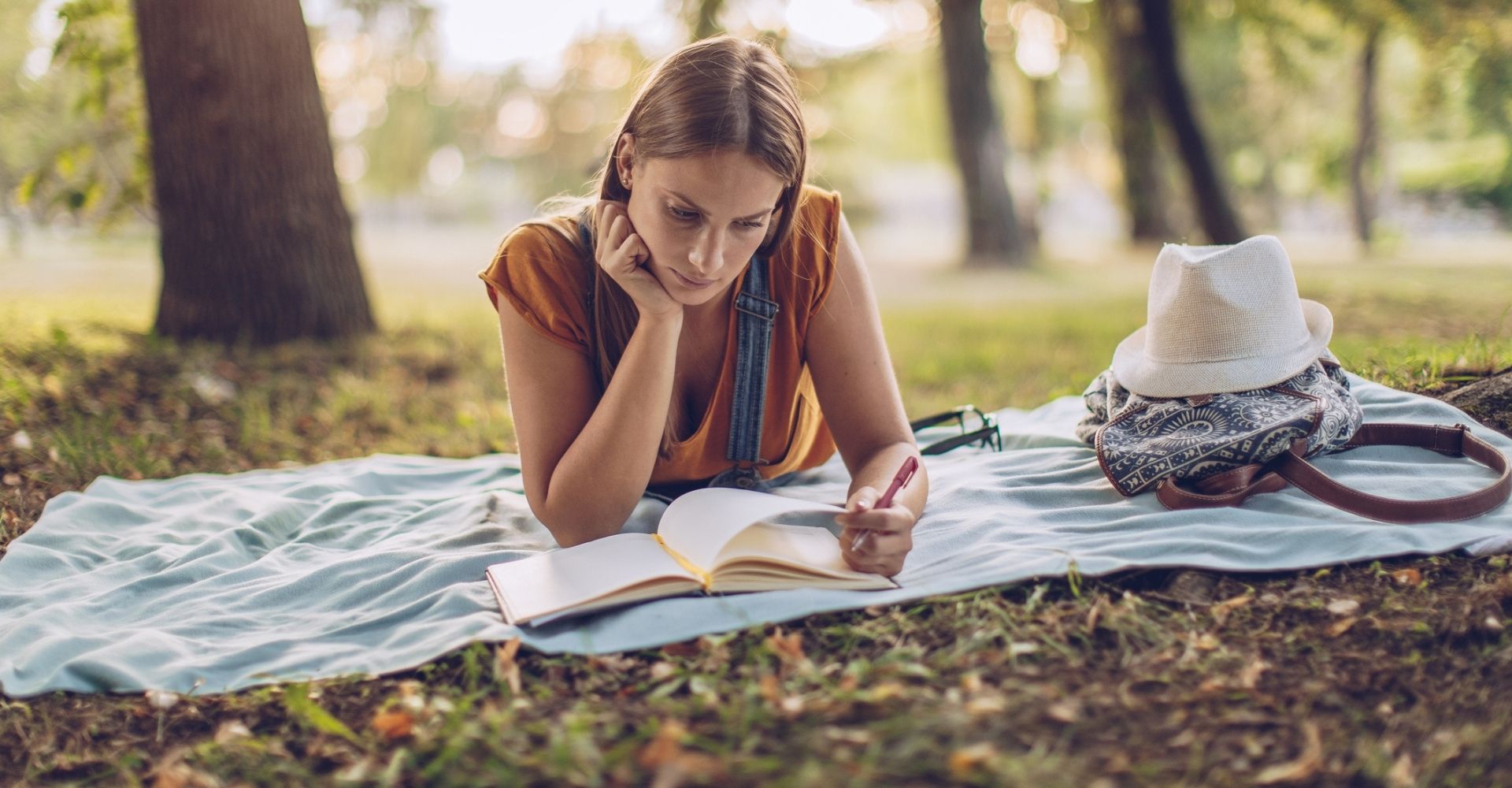 Giovane donna che legge un libro in un bosco, lettrice