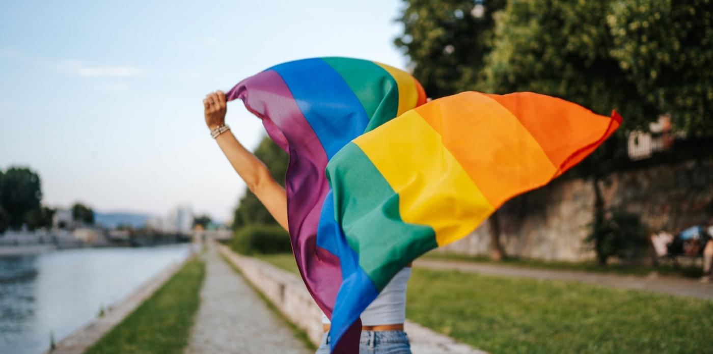 una ragazza sventola la bandiera arcobaleno, simbolo del movimento lgbtq+