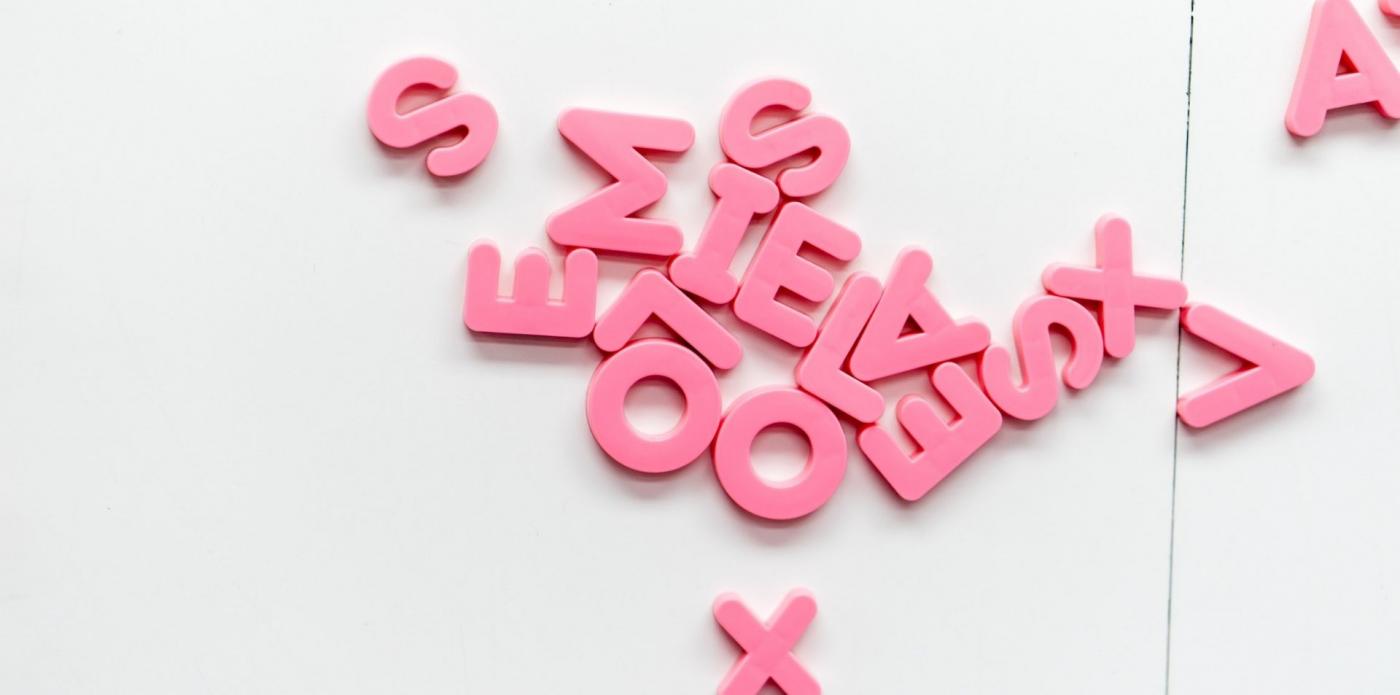 Alcune lettere dell'alfabeto in plastica sparpagliate su un piano bianco