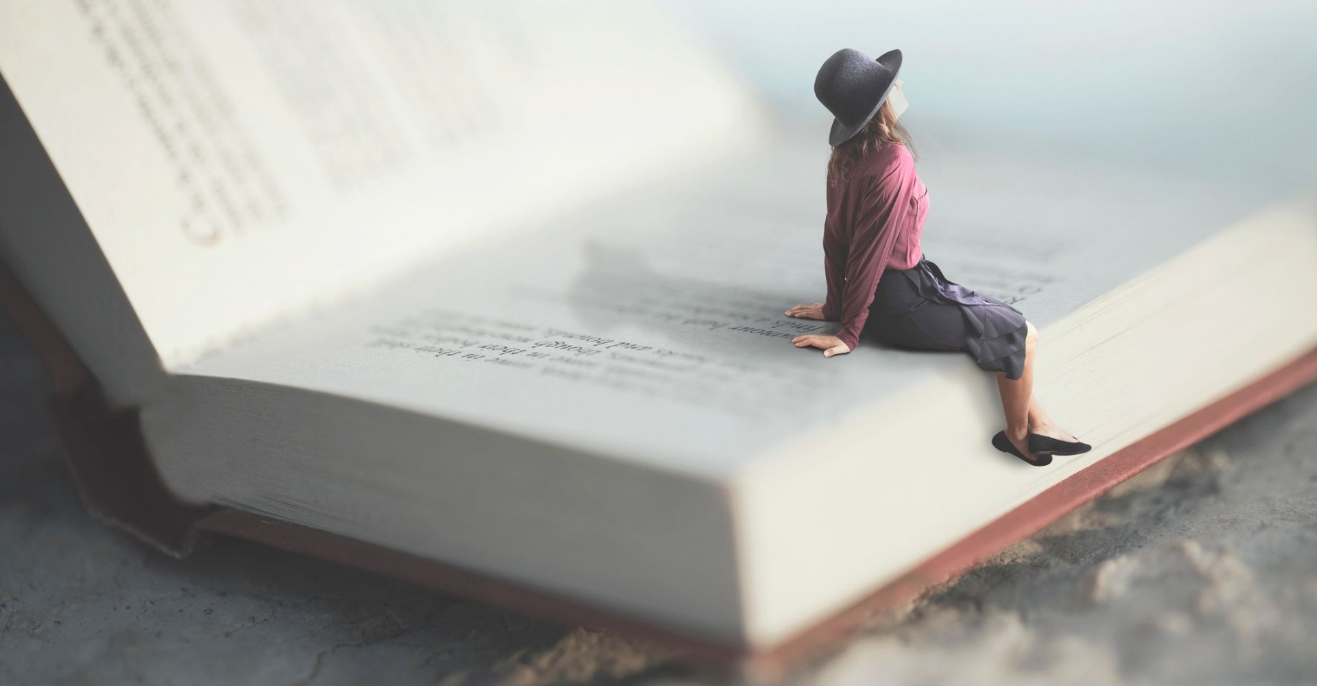 Una ragazza guarda verso l'alto seduta su un libro aperto gigante