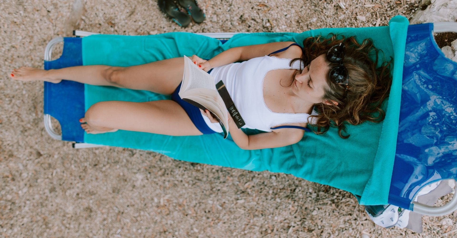 Veduta aerea di una ragazza che legge un libro su un telo da mare d'estate su una spiaggia