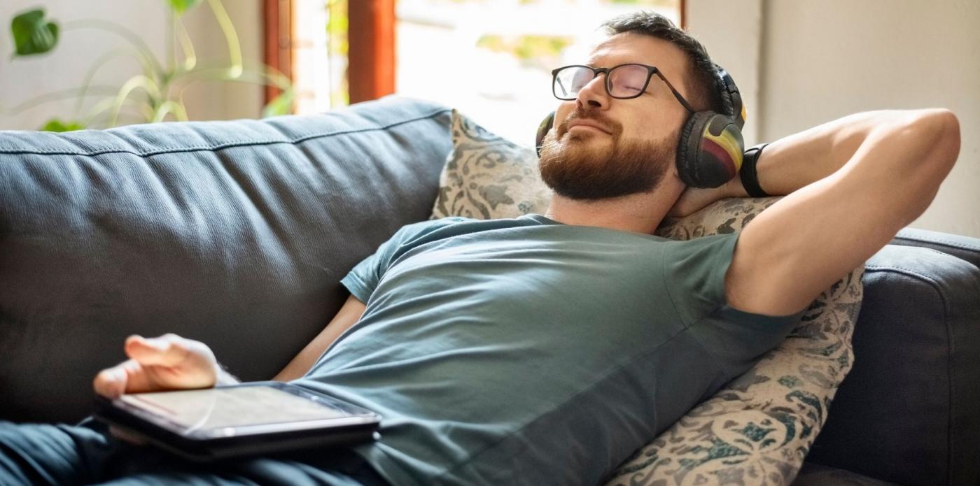 Ragazzo che ascolta un podcasto un audiolibro sul divano
