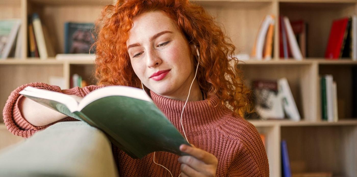 Donna che ascolta un podcast o audiolibro seduta su un divano