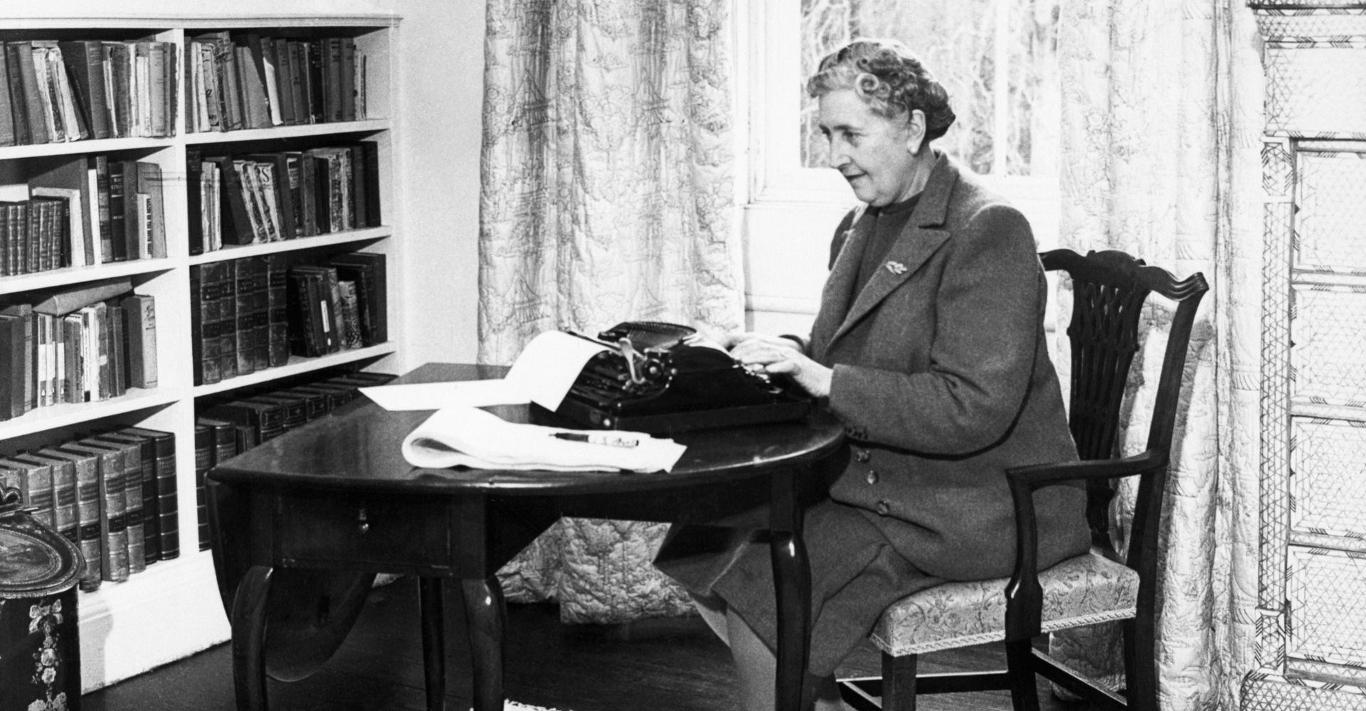 Agatha Christie seduta alla sua scrivania con una macchina da scrivere di fronte a sé