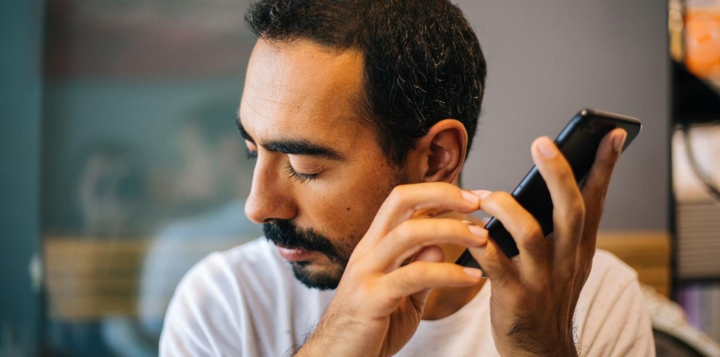 una persona con disabilità visive utilizza l'assistente vocale del telefono cellulare