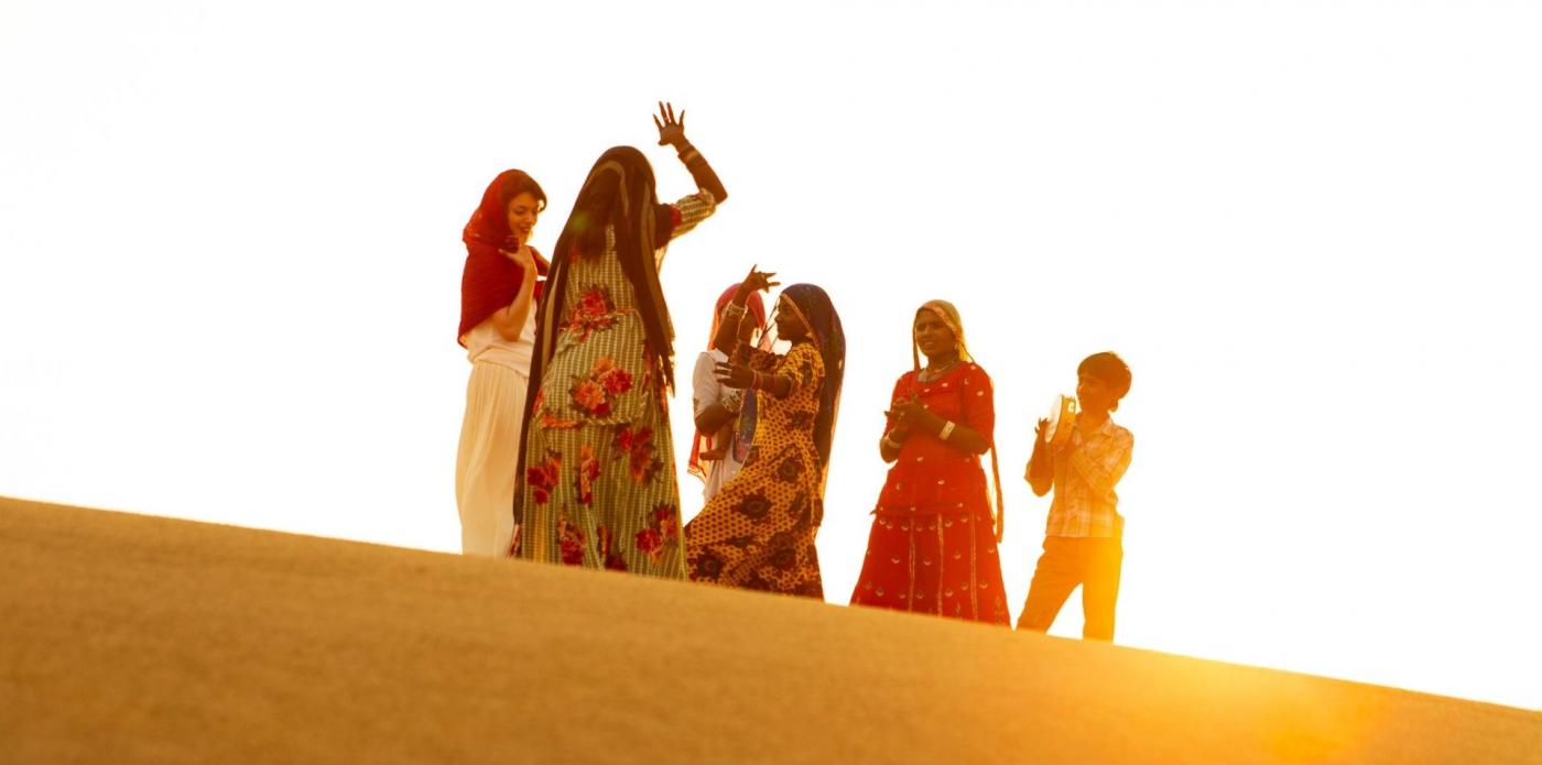 Delle donne appartenenti alla comunità Rom ballano nel deserto