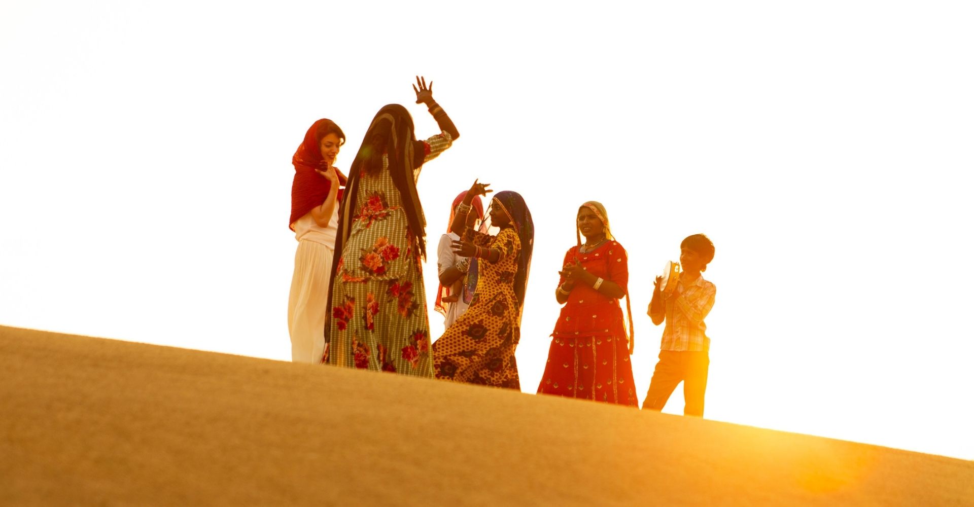 Delle donne appartenenti alla comunità Rom ballano nel deserto