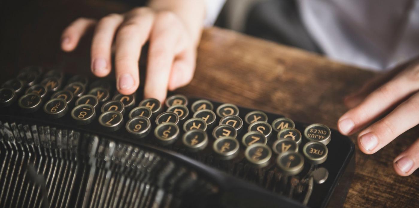 Due mani appoggiate sopra una macchina da scrivere su una scrivania