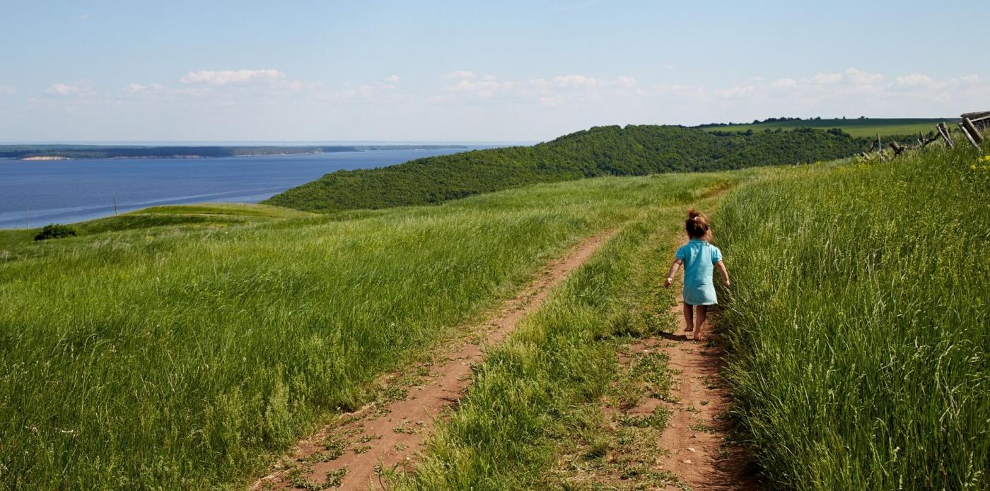 Una bambina cammina su un prato vicino al fiume Volga