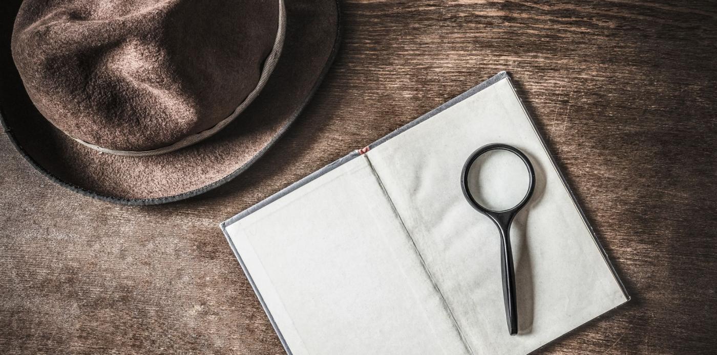 Un libro, una lente di ingrandimento e un cappello su un tavolo