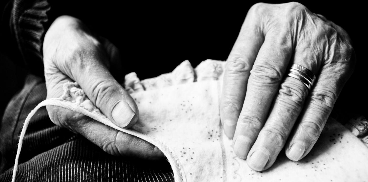 Foto in bianco e nero che raffigura in primo piano due mani di donna intente a lavorare a maglia