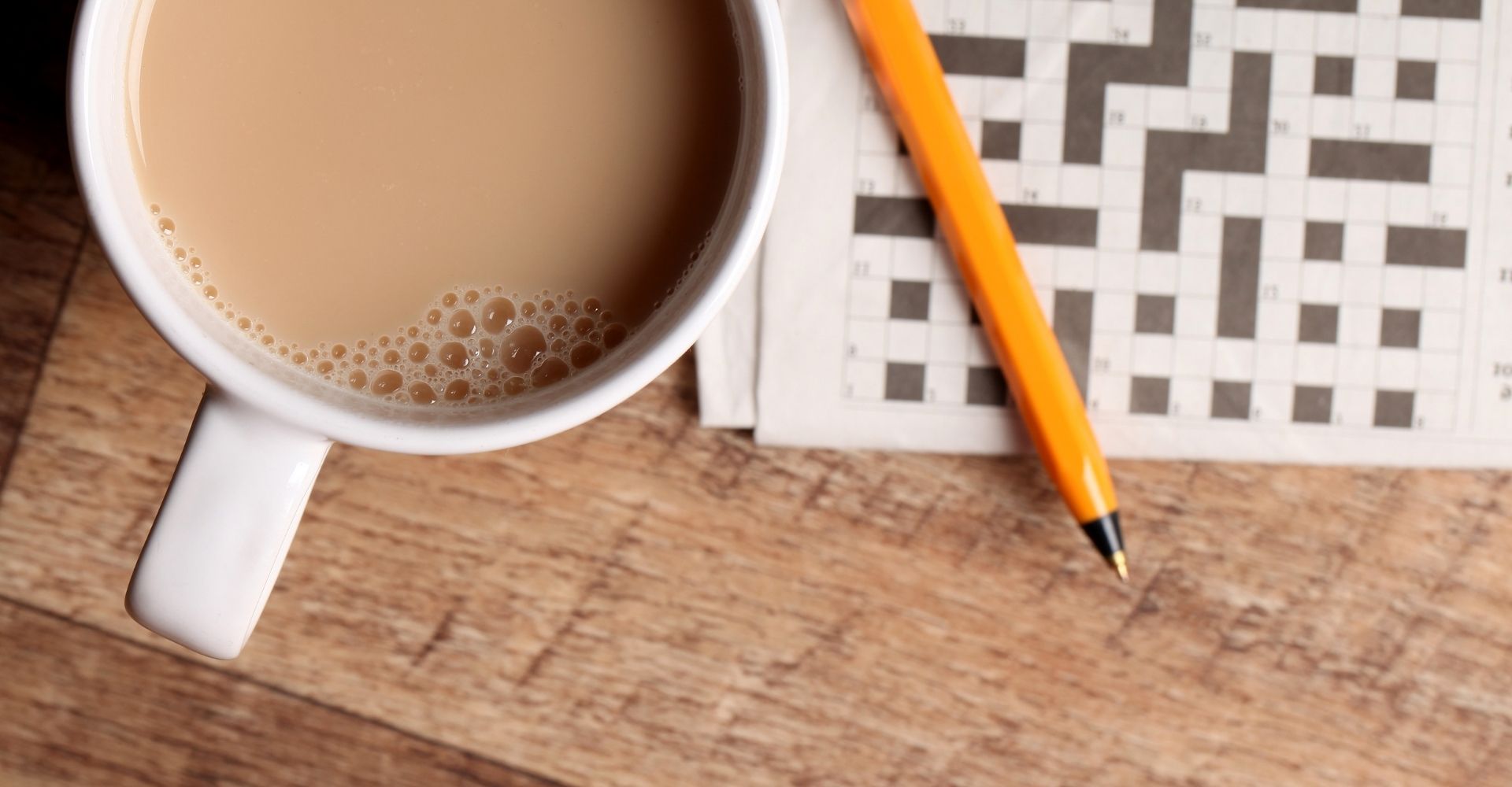 Una tazza di cioccolata calda, una penna e uno schema di parole crociate su un tavolo