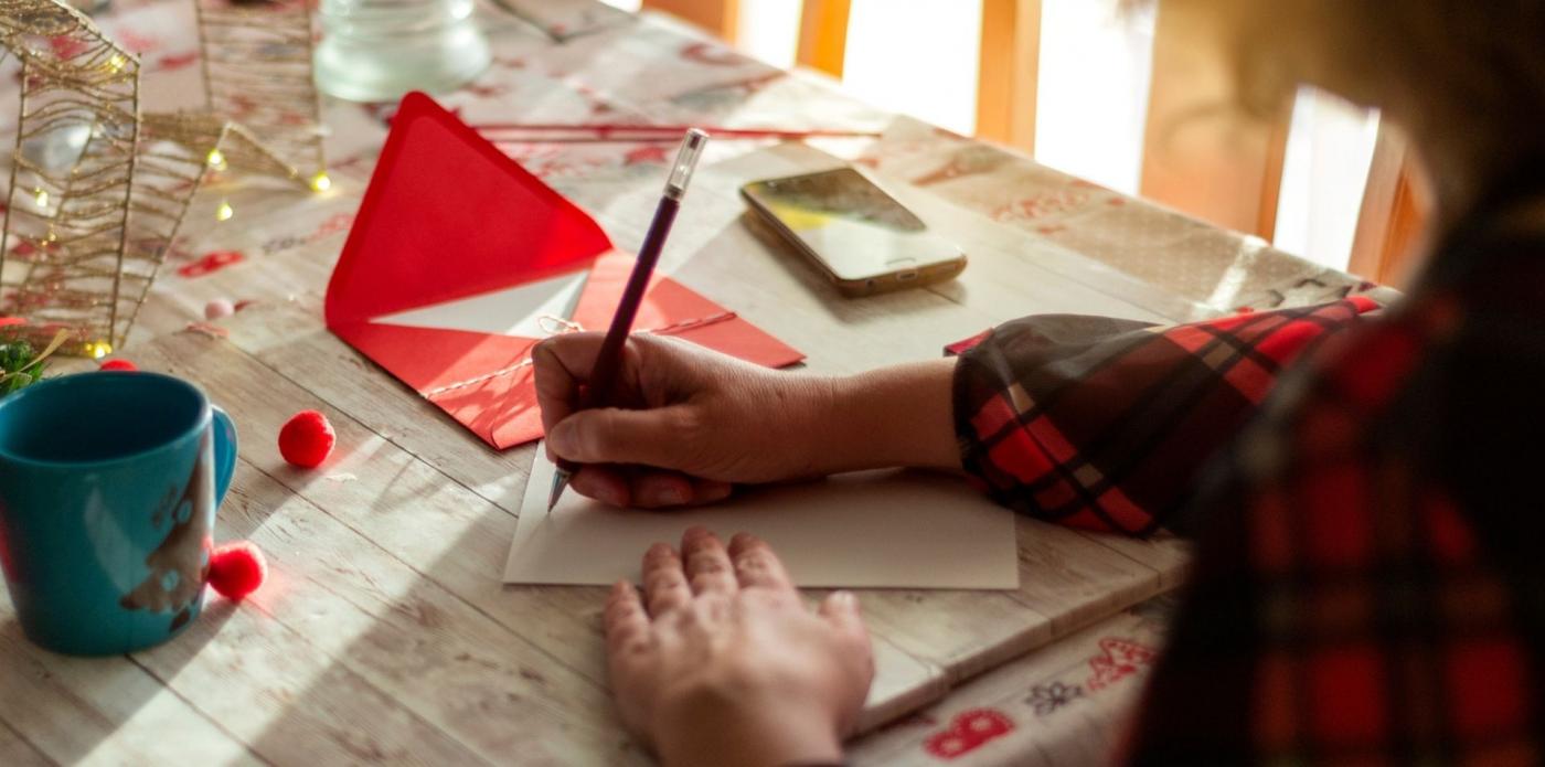 Una ragazza scrive un biglietto di auguri su un tavolo