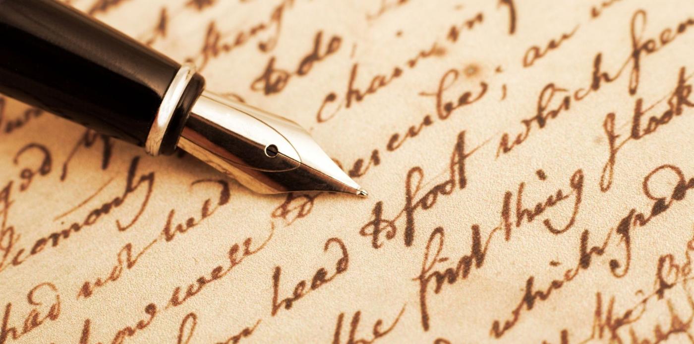 Una penna stilografica appoggiata su una carta anticata riempita da righe scritte a mano