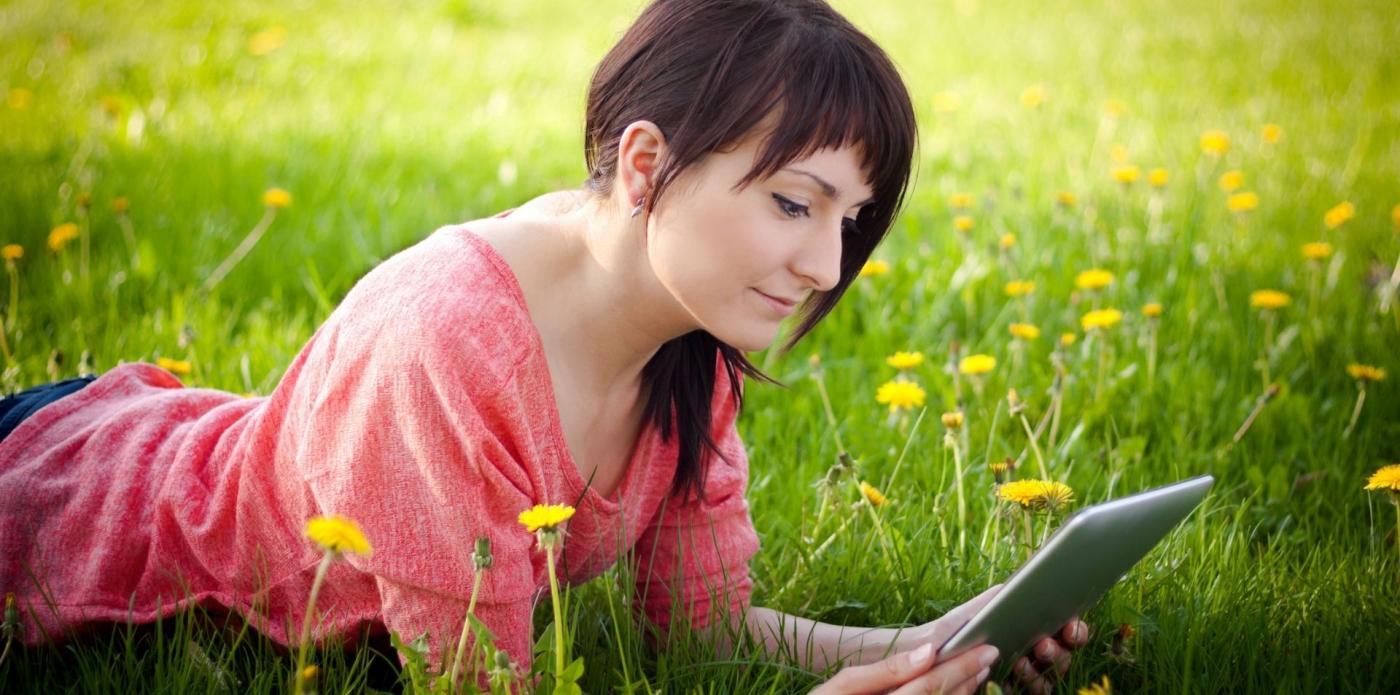 Giovane donna legge lettura ebook primavera parco prato fiori