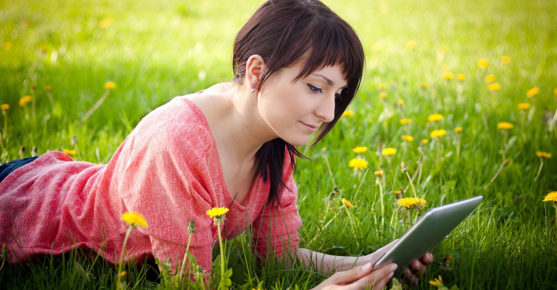 Giovane donna legge lettura ebook primavera parco prato fiori