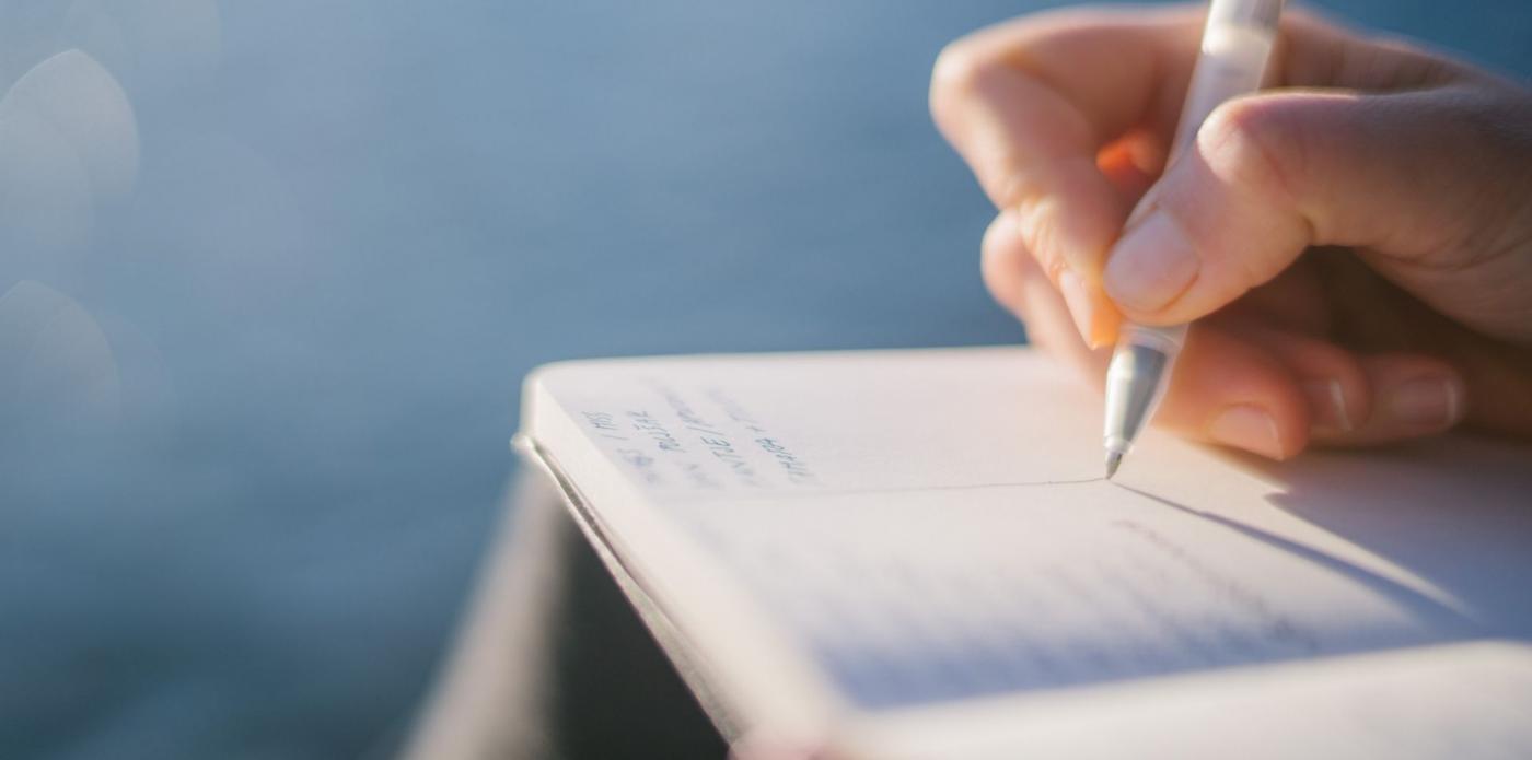 una penna che scrive su un quadernino