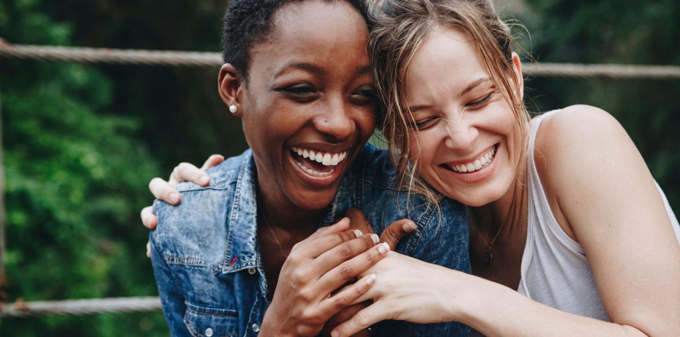 Due ragazze si abbracciano ridendo in segno di amicizia