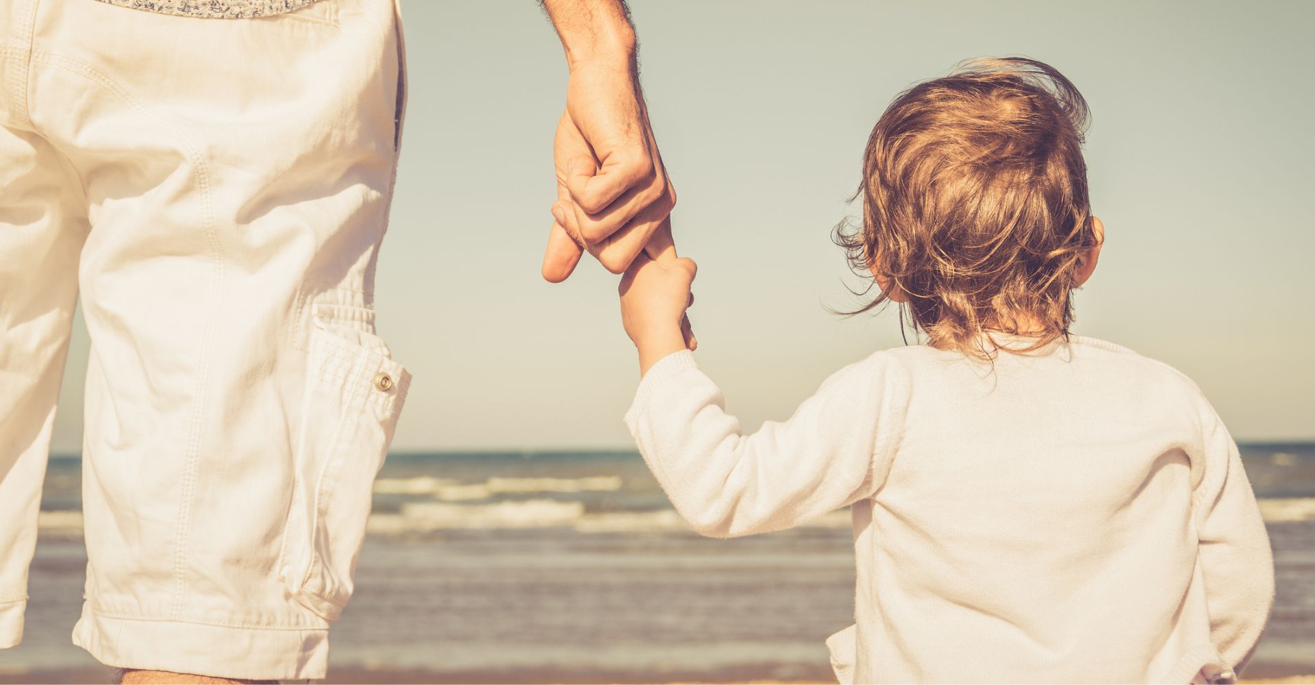 papà che tiene per mano il figlio di fonte al mare - copertina per articolo sui libri della festa del papà