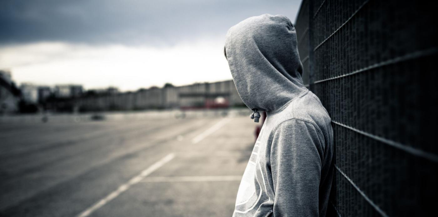 Solitario uomo appoggiato su una staccionata, adolescente ribelle