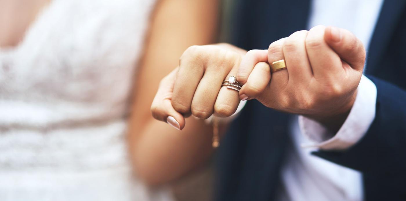 Una donna e un uomo uniti in matrimonio mostrano in primo piano le loro fedi nuziali
