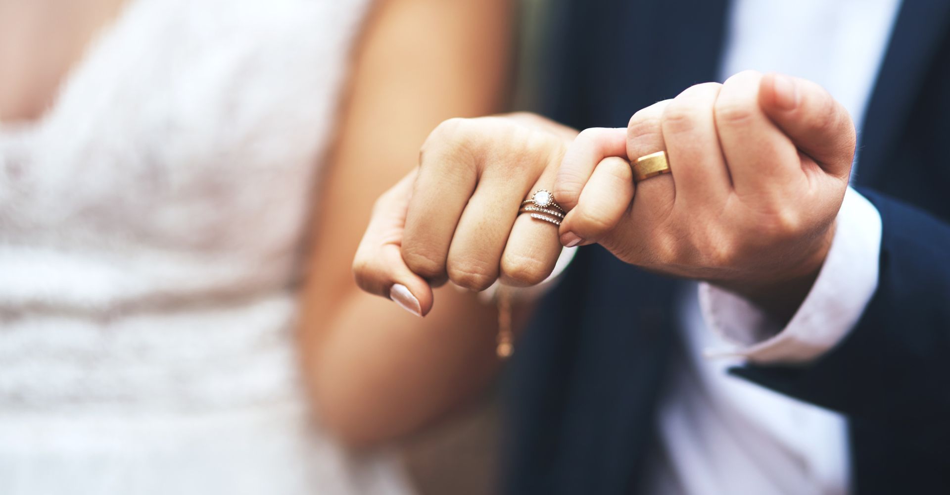 Una donna e un uomo uniti in matrimonio mostrano in primo piano le loro fedi nuziali