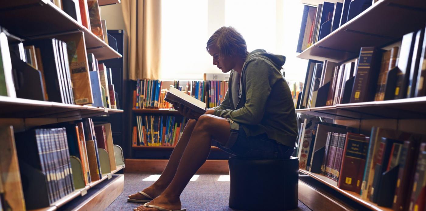 Ragazzo legge un libro in biblioteca