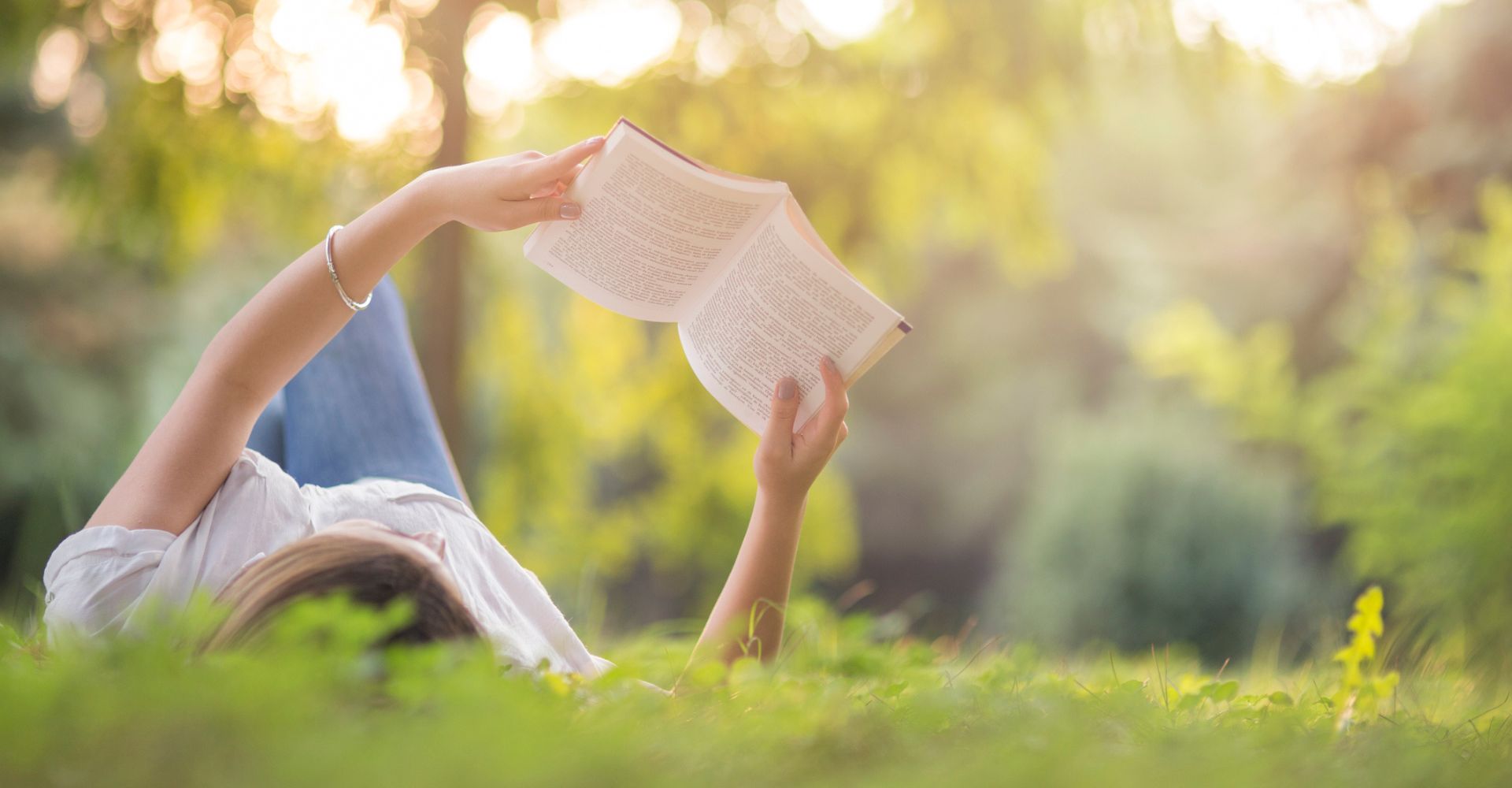 una ragazza legge un libro sdraiata sul prato