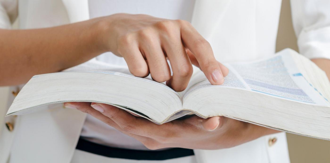 Una ragazza tiene tra le mani e sfoglia un dizionario