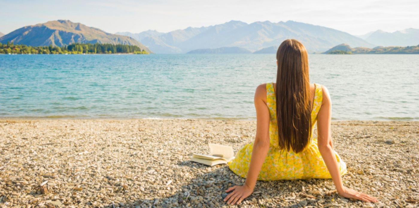 Donna osserva l'orizzonte davanti con un libro
