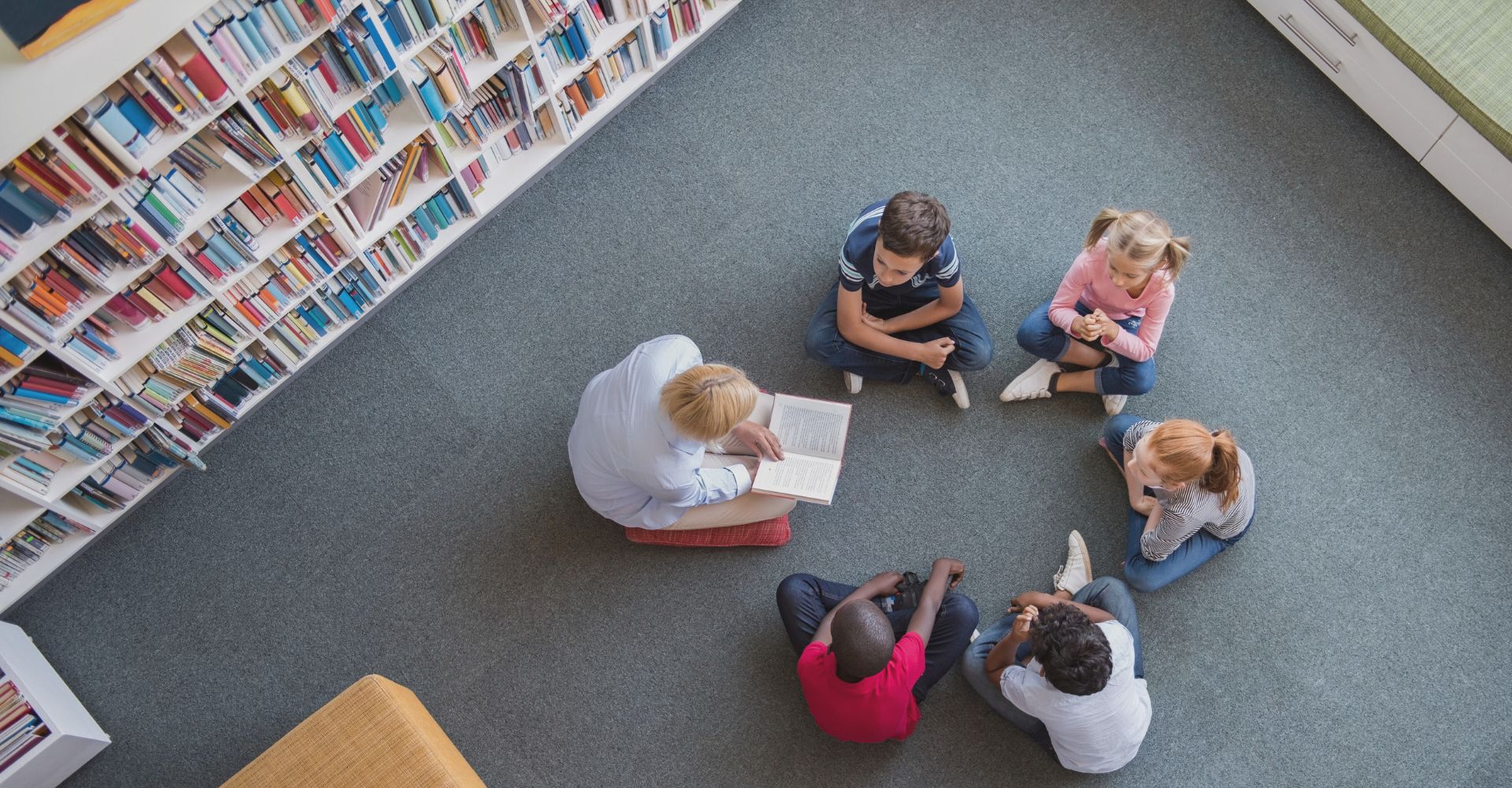 bambini bambine leggono nella biblioteca della scuola