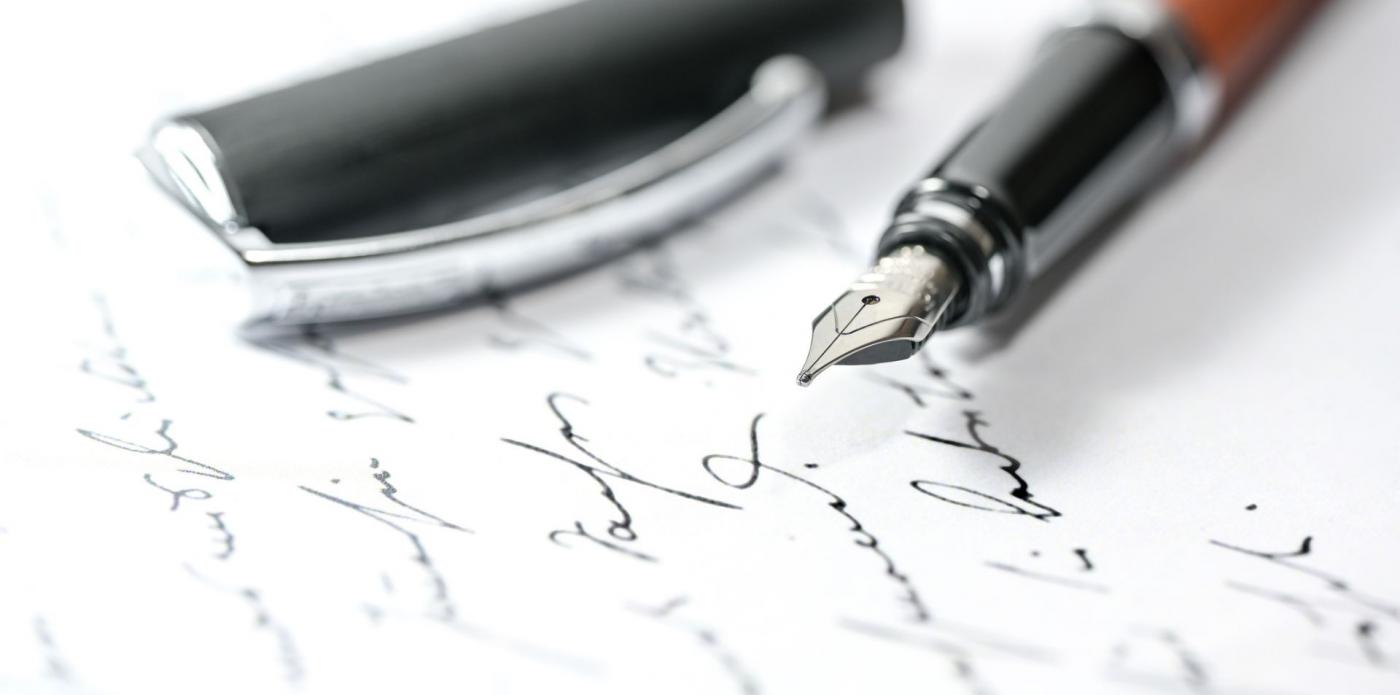 Primo piano di una penna stilografica aperta che è stata appoggiata su un foglio con sopra scritte delle frasi
