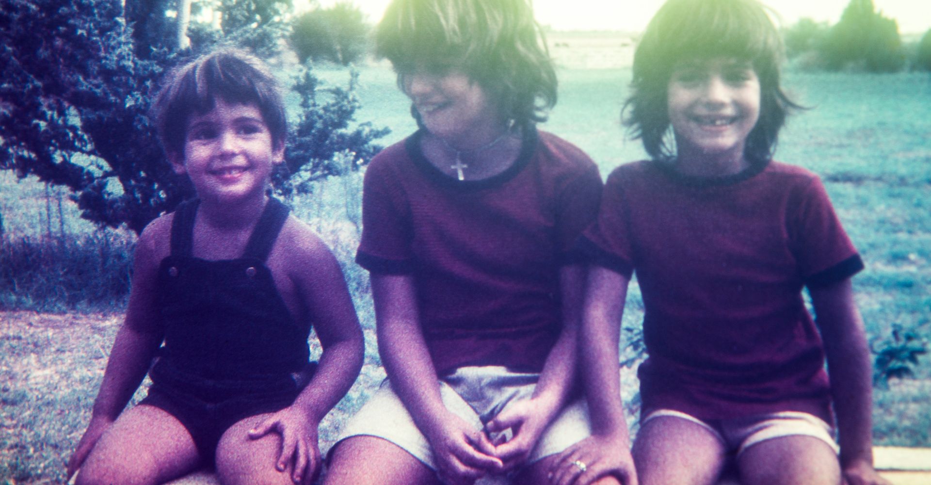 Una foto vintage che ritrae tre fratelli e sorelle seduti vicini e sorridenti