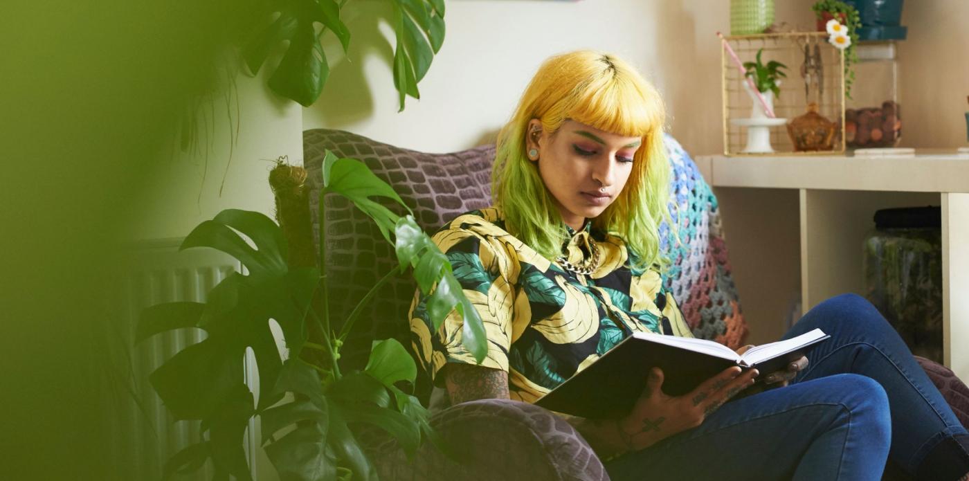 Ragazza in poltrona che legge assorta un libro