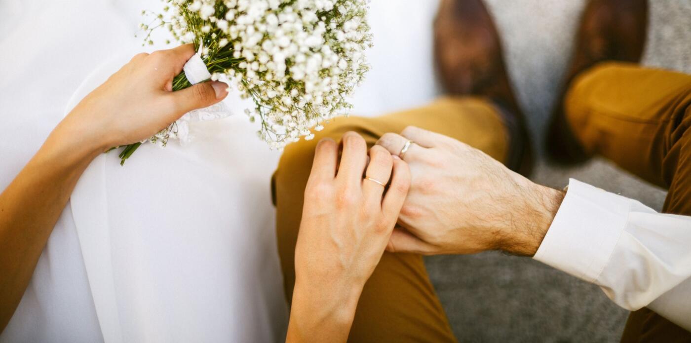 Primo piano dall'alto delle mani di due novelli sposi che si tengono per mano