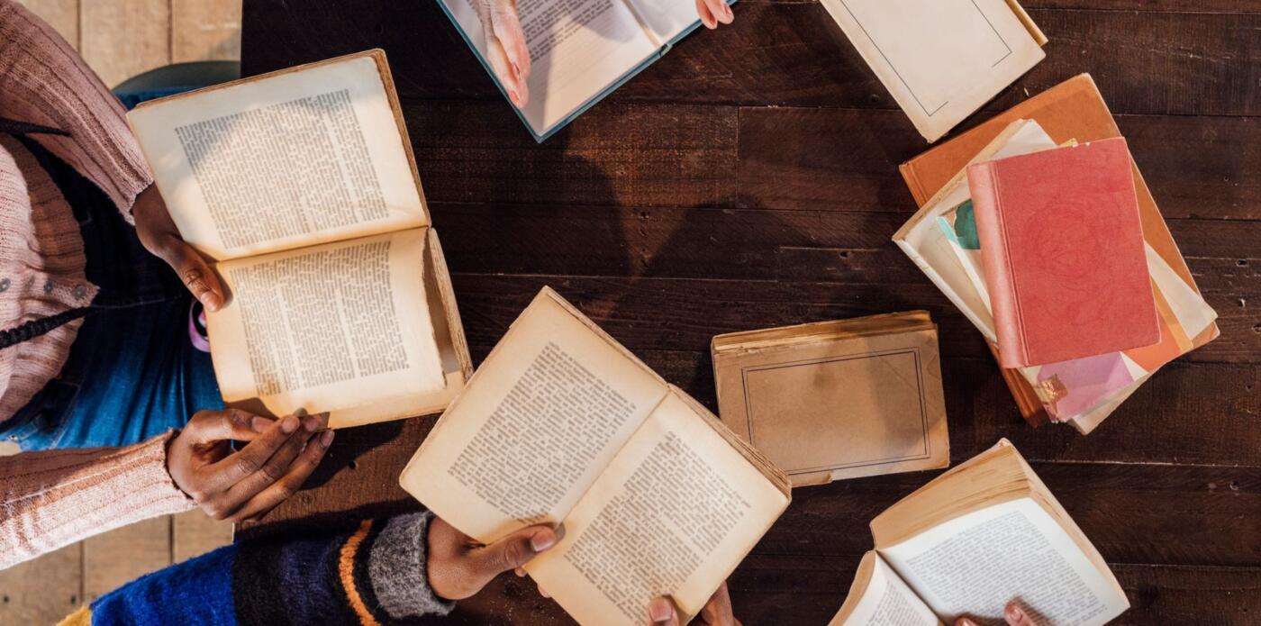 Un gruppo di persone fotografato dall'alto legge insieme durante un bookclub