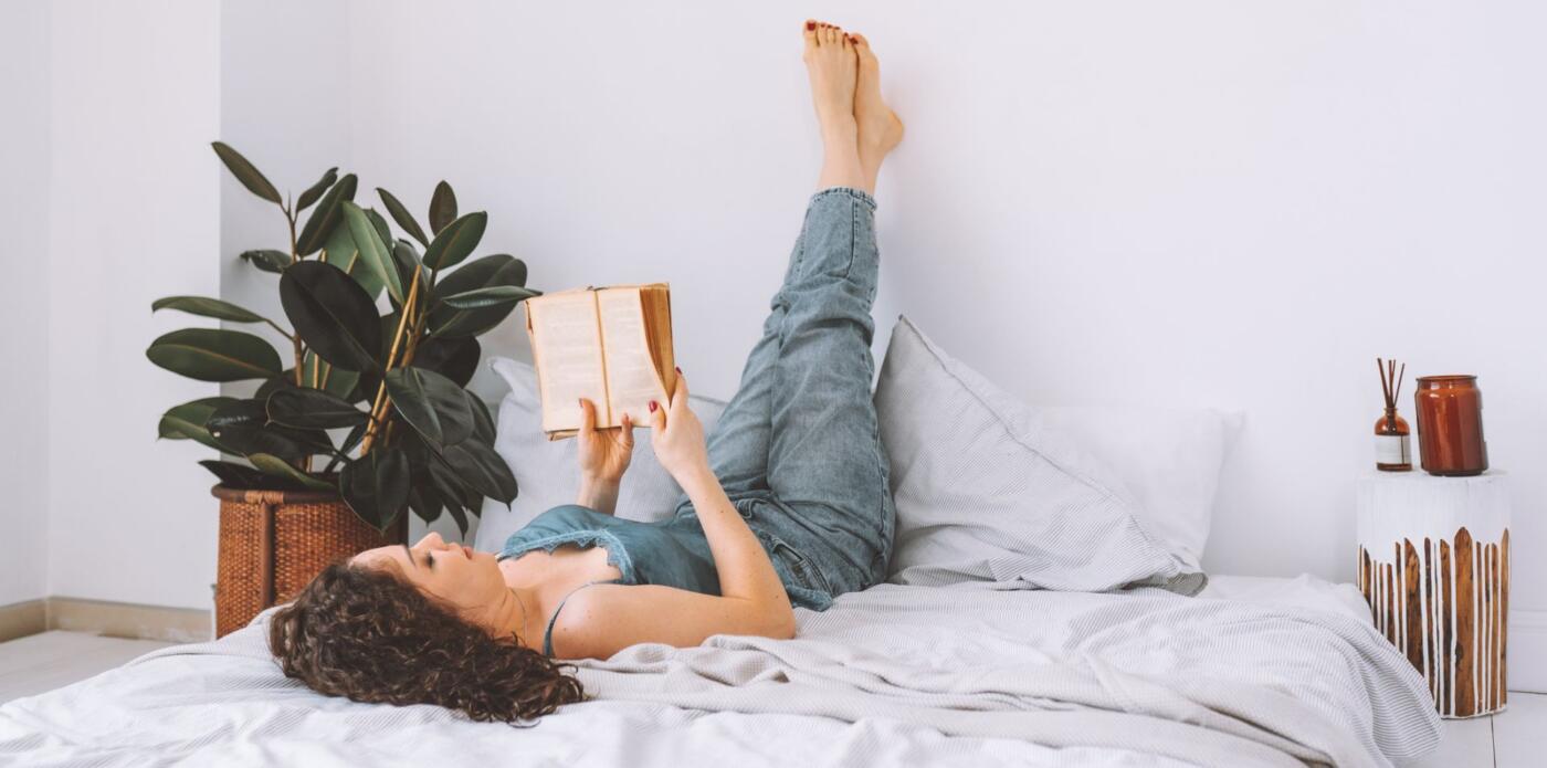 Una ragazza sdraiata sul letto legge un libro