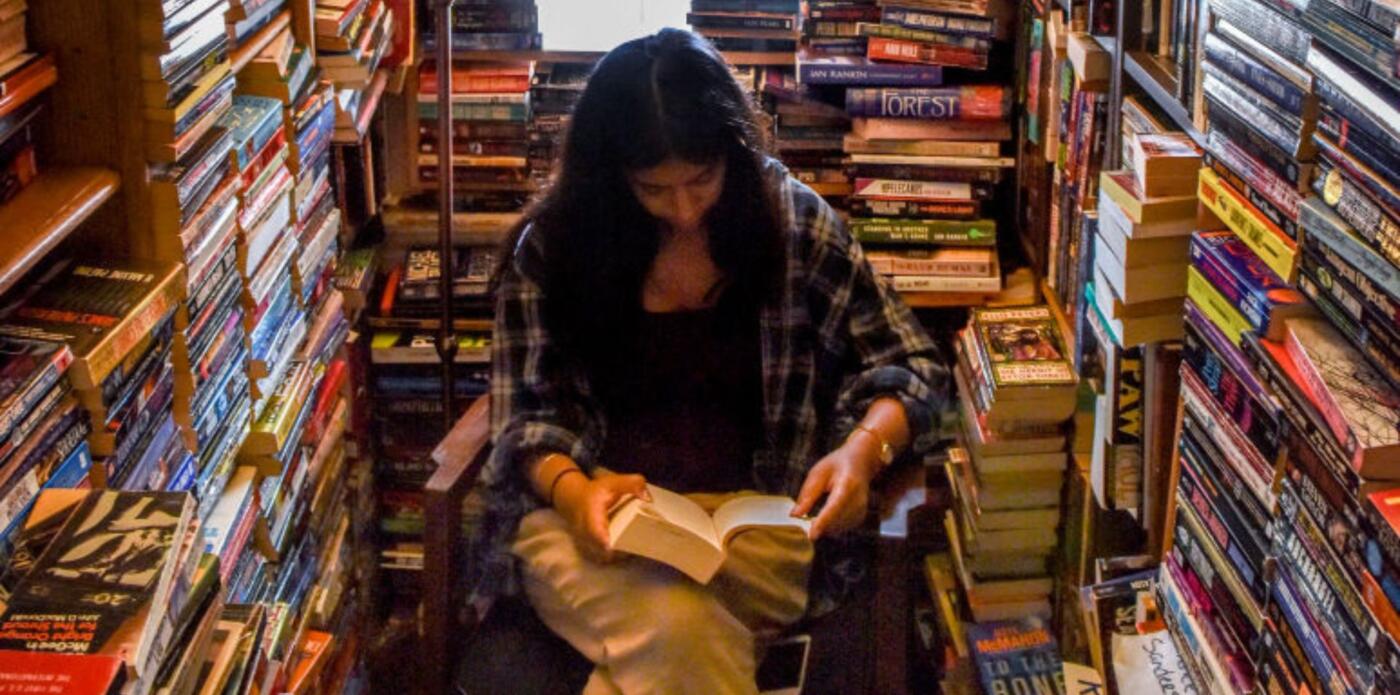 Ragazza legge tra pile di libri