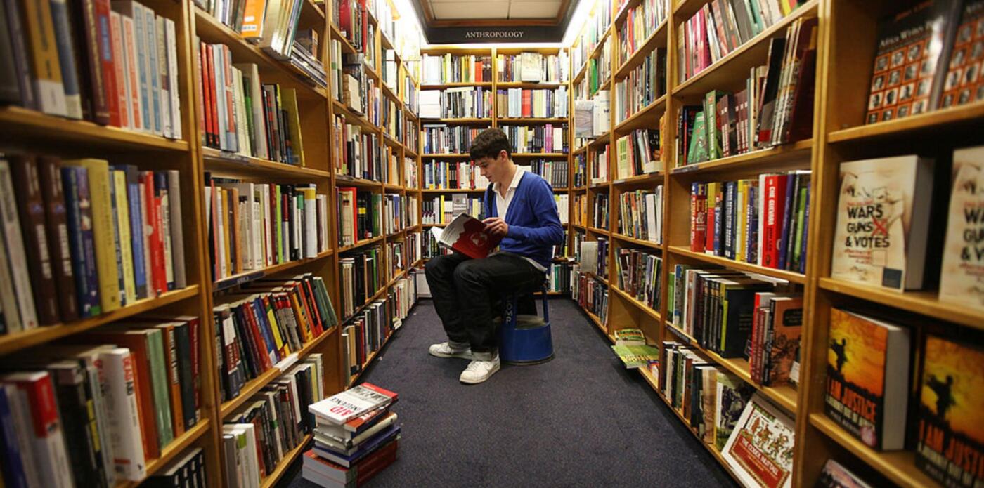 Ragazzo legge in biblioteca