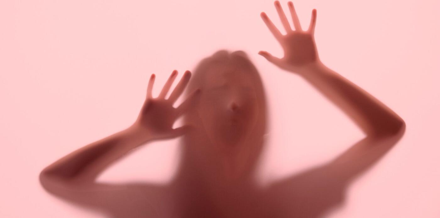 La silhouette di una figura femminile inquietante poggiata contro un vetro